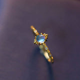 Gold ring with a blue gemstone on a dark textured background